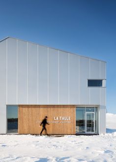 a person walking in the snow near a building