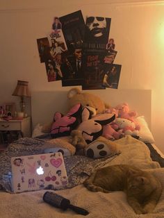 an orange cat laying on top of a bed next to stuffed animals and a laptop