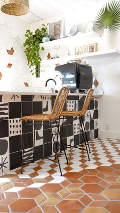 two wicker chairs sit in front of a black and white tiled counter top with a printer on it