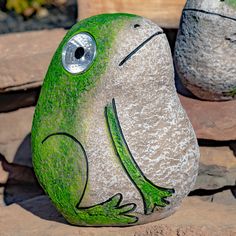 a rock with a frog painted on it sitting next to another rock in the background