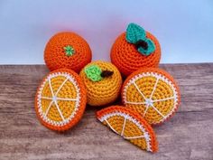 crocheted oranges with green leaves on them are sitting on a wooden surface