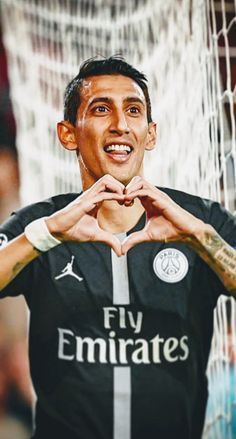 a man making a heart with his hands while standing in front of a soccer net