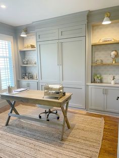 an office with gray cabinets and a desk in the middle is shown on top of a beige rug