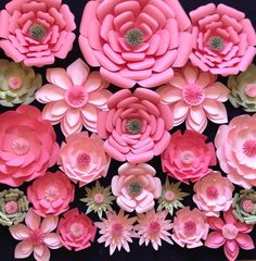 pink paper flowers are arranged on a black surface