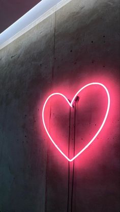 a heart shaped neon sign on the side of a building