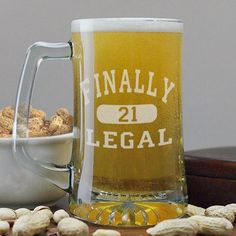 a beer mug sitting on top of a table next to nuts