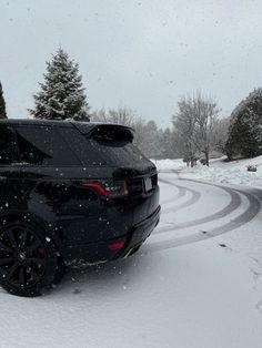 a black car driving down a snow covered road