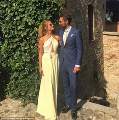 a man and woman standing next to each other in front of a building with ivy growing on it