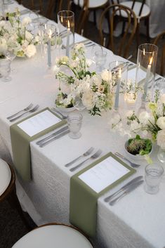 the table is set with white flowers and silverware for an elegant dinnereonal