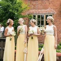 the bridesmaids are wearing yellow dresses and holding umbrellas in front of a brick building