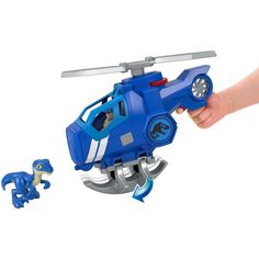 a hand holding a toy helicopter next to a small dinosaur