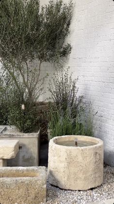 two cement planters sitting next to each other in front of a white brick wall