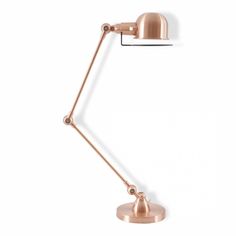 the copper desk lamp is on top of a white wall and has a metal base