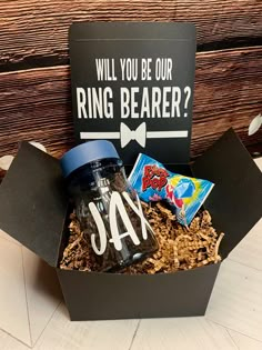 a gift box filled with chips, candy and a jar that says will you be our ring bearer?