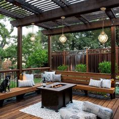 a dog sitting on a wooden deck next to a fire pit and bench with pillows