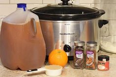 a crock pot, orange and other ingredients are on the counter next to an electric pressure cooker