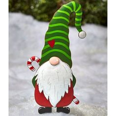 a green and white striped gnome with candy canes on his nose in the snow