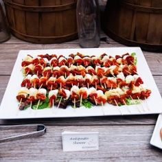 a platter of skewered meats and vegetables on a wooden table next to wine barrels