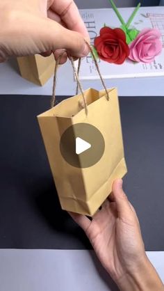 someone is holding a brown paper bag with flowers on it and the video below shows how to make an origami flower