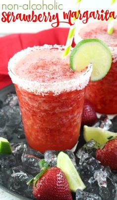 two glasses filled with strawberry margaritas on top of ice and strawberries next to each other