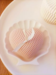 a heart shaped object sitting on top of a white plate next to cupcakes