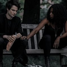 a man and woman sitting on a bench next to a dog