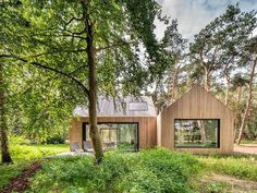 a house in the woods surrounded by trees and grass, with two windows on each side