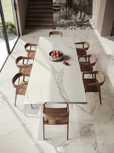 a dining room table with chairs and fruit bowl on the table in front of it