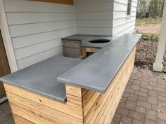 an outdoor kitchen built into the side of a house with concrete counter tops and drawers