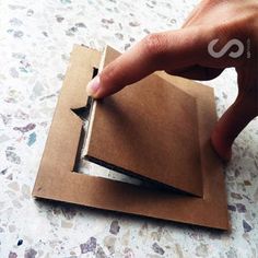 a person is cutting out some paper with a small piece of cardboard on the floor