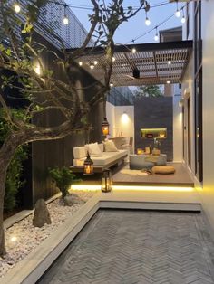 an outdoor living area is lit up with string lights and decorative lighting, as well as a tree