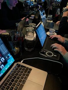 three people sitting at a bar using laptops