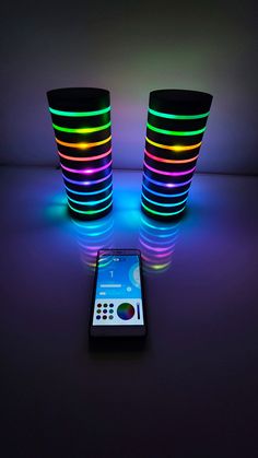 a cell phone sitting next to two lit up speakers