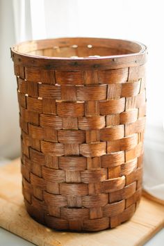 a woven basket sitting on top of a wooden cutting board next to a white window