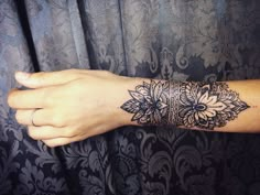 a woman's arm with a black and white tattoo design on the left wrist