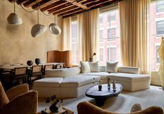 a living room filled with lots of furniture next to a large window covered in curtains