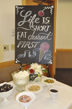 a table topped with lots of desserts next to a chalkboard that says life is short, eat dessert first