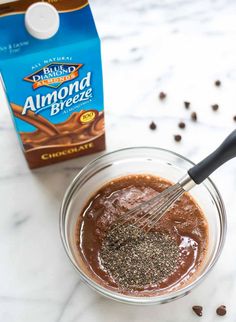 a glass bowl filled with chocolate pudding next to a carton of almond milk