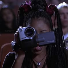 a woman holding a video camera up to her face in front of a group of people