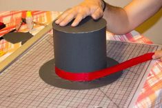 someone is making a top hat out of construction paper and red ribbon on the table