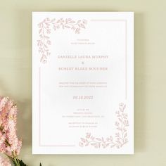 a wedding card with pink flowers and greenery on the front is shown next to it