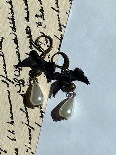 Victorian style earrings with a black bow and dangly pearl shaped beads. Black Bow Jewelry For Evening, Chic Black Earrings For Wedding, Black Dangle Pearl Earrings, Elegant Black Pearl Earrings, Black Pearl Drop Earrings For Formal Events, Black Pearl Drop Earrings For Formal Occasions, Elegant Evening Jewelry With Black Ribbon, Chic Black Jewelry With Bow, Black Teardrop Pearl Earrings Gift