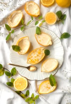 some lemons are sitting on a plate with spoons and leaves next to them