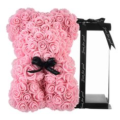 a teddy bear made out of pink roses with a black bow on it's head