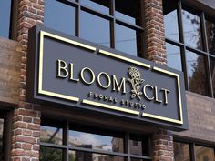 a sign that says bloom city floral studio on the side of a brick building with glass windows