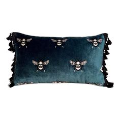 a blue velvet pillow with two bees on it and fringe trimming around the edges