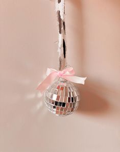 a disco ball hanging from the ceiling with a pink bow on it's end