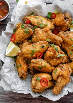 chicken wings with peppers, limes and cilantro in a paper bowl on a wooden table