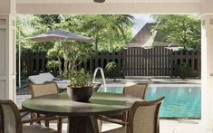 an outdoor dining table with umbrellas and chairs next to a pool in the background