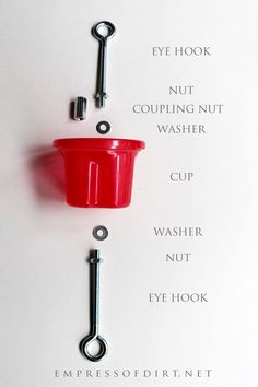 a red cup hanging from the side of a hook on a white wall with words written below it